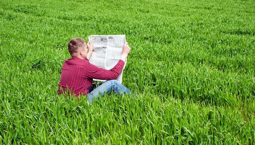 Bild eines Mannes mit einer Zeitung im Feld sitzend